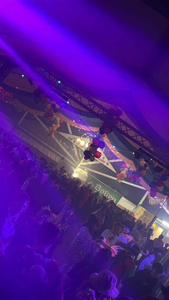 Bunte Lichter und eine tanzende Menschenmenge auf einer Feier.