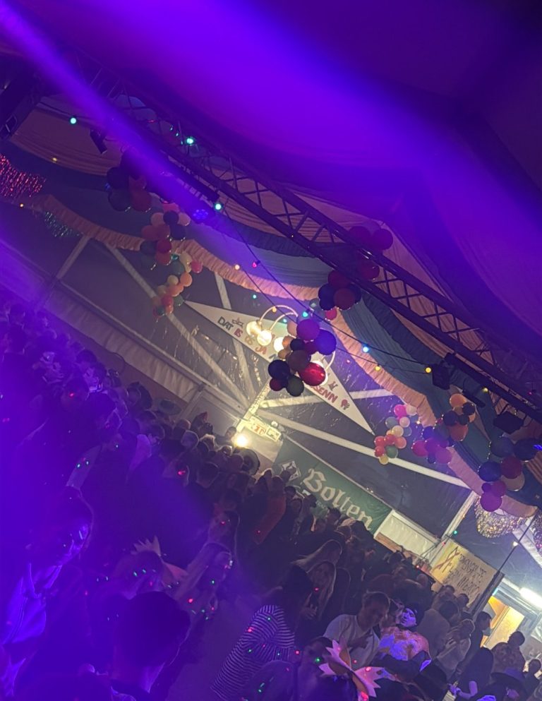 Bunte Lichter und Dekorationen in einer lebhaften Veranstaltung mit vielen Menschen und der Musik von DJ Driessen.