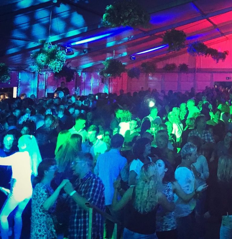Bunte Lichter und tanzende Menschen auf einer lebhaften Party mit DJ Driessen.