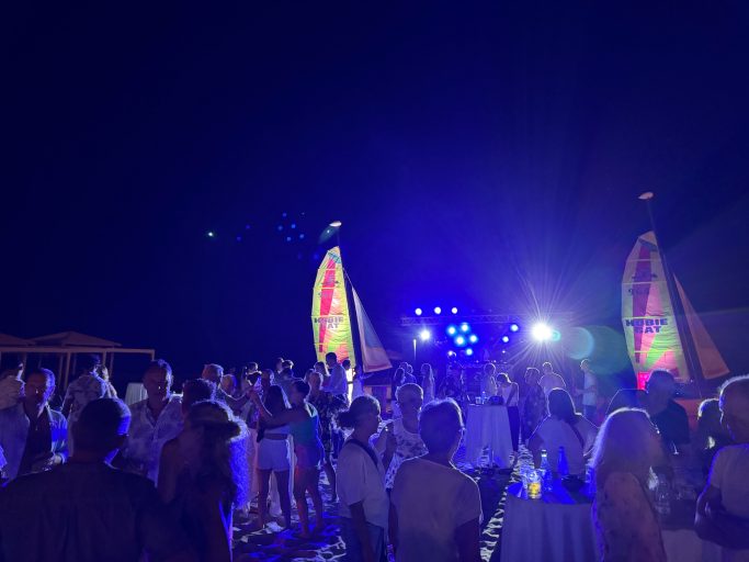Menschen tanzen und feiern auf einer lebhaften Nachtveranstaltung am Strand.
