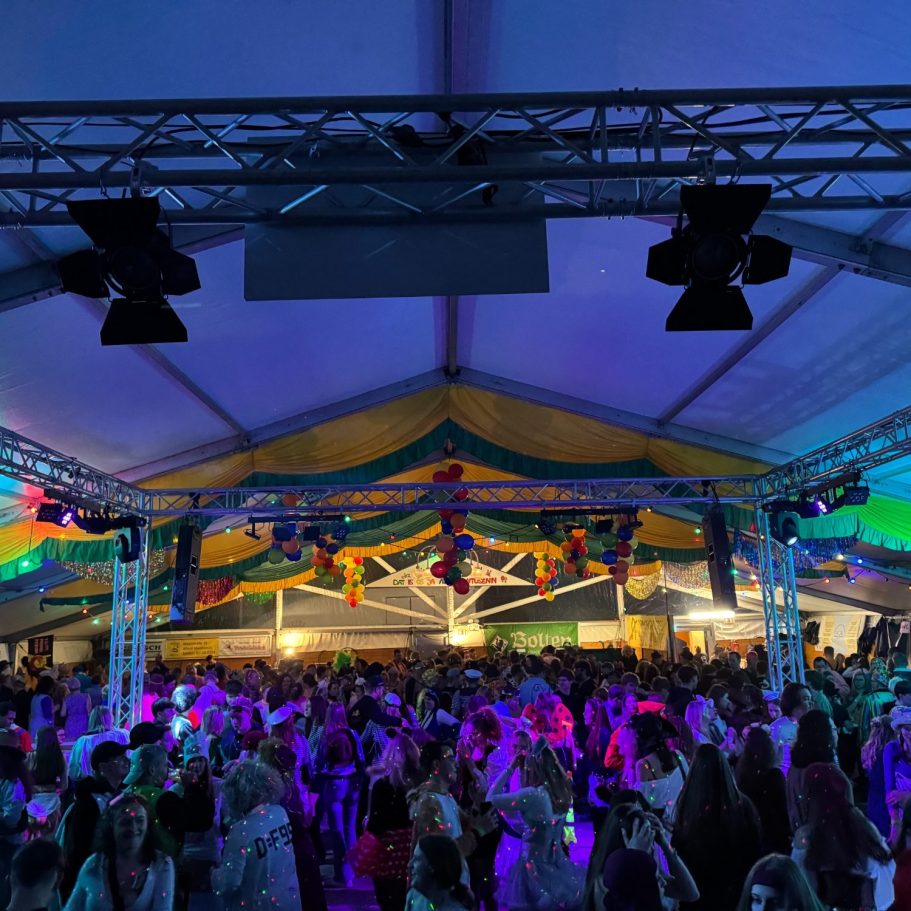 Bunte Menschenmenge in einem festlich beleuchteten Zelt während einer Feier mit DJ Driessen.