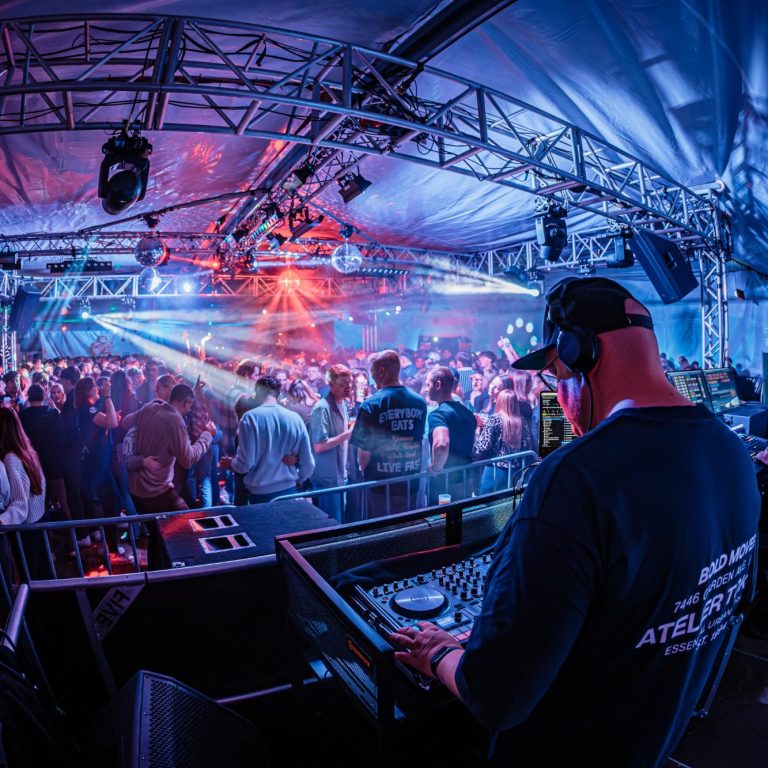 DJ Driessen legt Musik auf, während eine begeisterte Menge auf der Tanzfläche feiert.
