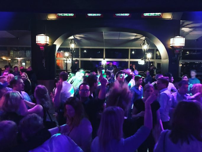 Menschen tanzen in einem lebhaften Club mit bunten Lichtern.