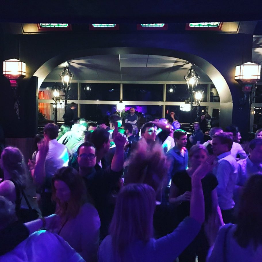 Menschen tanzen und feiern in einem lebhaften Nachtclub mit bunten Lichtern.