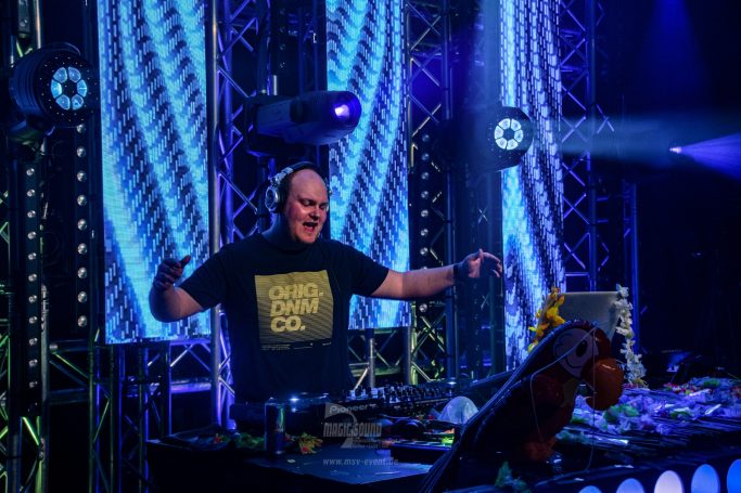 DJ an einem Mischpult mit bunten Lichtern und einer energischen Atmosphäre.