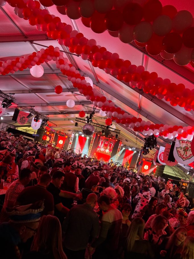 Voller Festsaal mit roten Ballons und Licht, Menschen feiern bei event.
