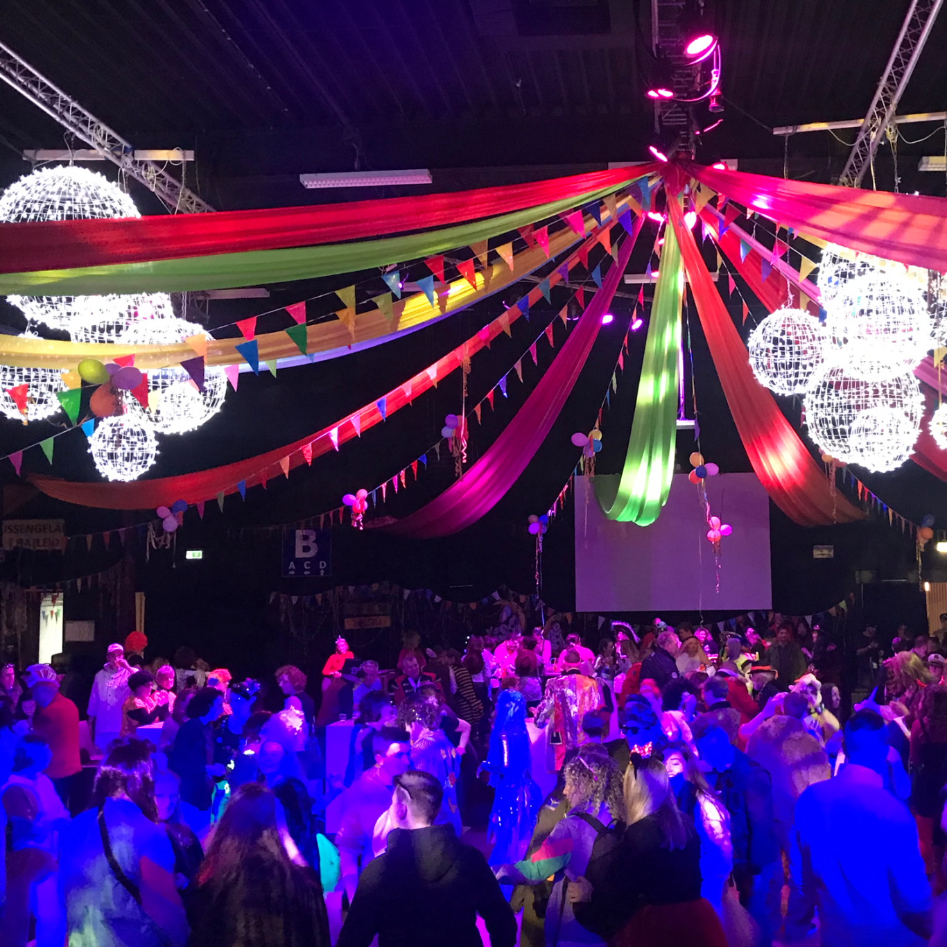 Bunte Lichter und Dekorationen über einer tanzenden Menschenmenge in festlicher Atmosphäre mit DJ Driessen.