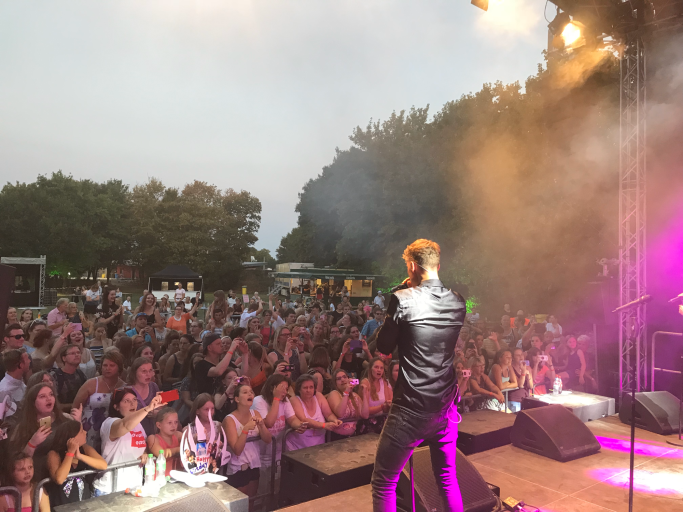 Musiker steht auf der Bühne vor begeistertem Publikum bei einem Konzert.