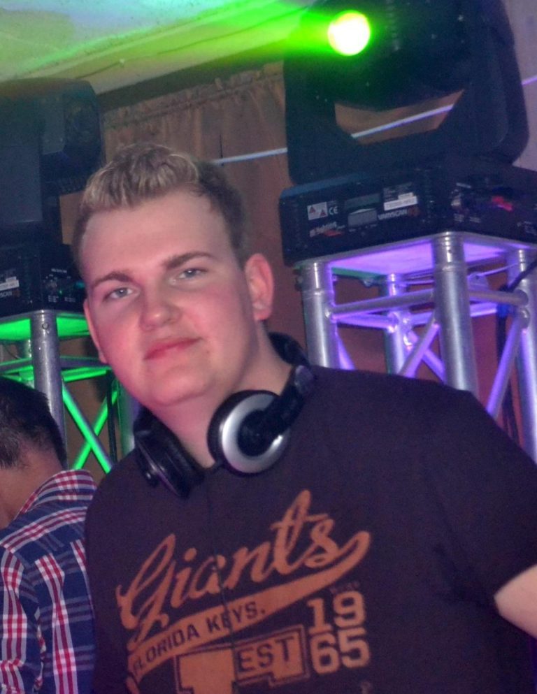DJ Driessen in jungen Jahren mit Kopfhörern auf einem DJ-Pult, umgeben von bunten Lichtern.